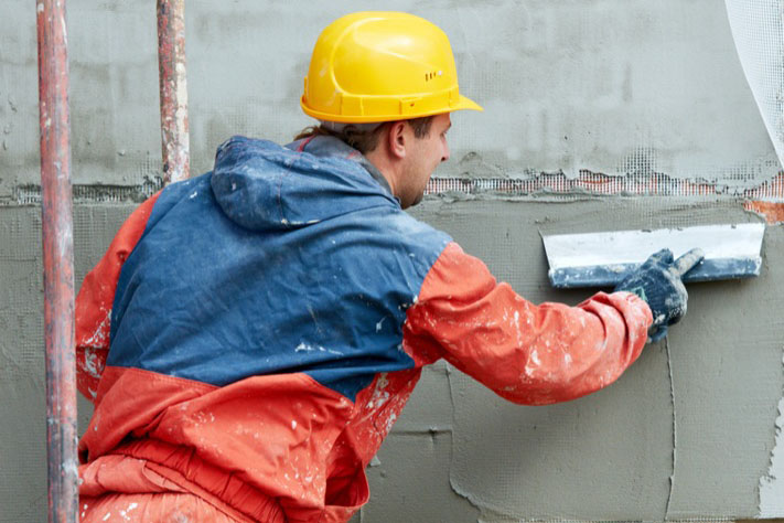 Facade Plasterer builder working at outdoor wall renovation decoration with float