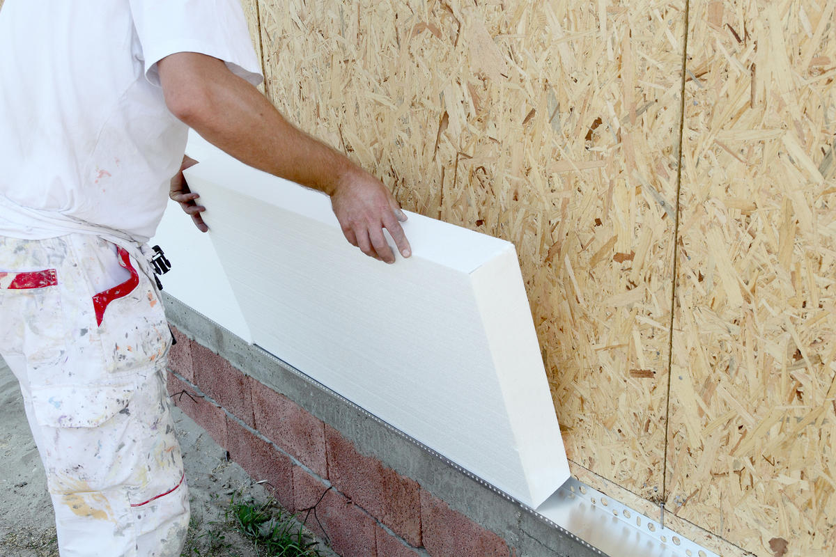 Worker placing styrofoam sheet insulation to the wall