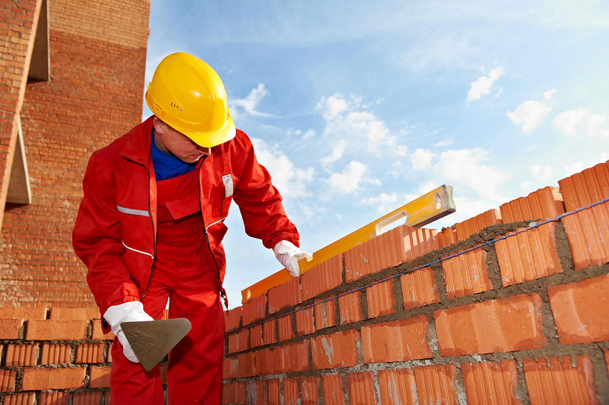 construction mason worker bricklayer making a brickwork with trowel and cement mortar